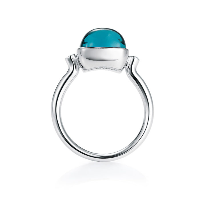 Gold ring with blue gemstone on guilloched surface with diamonds