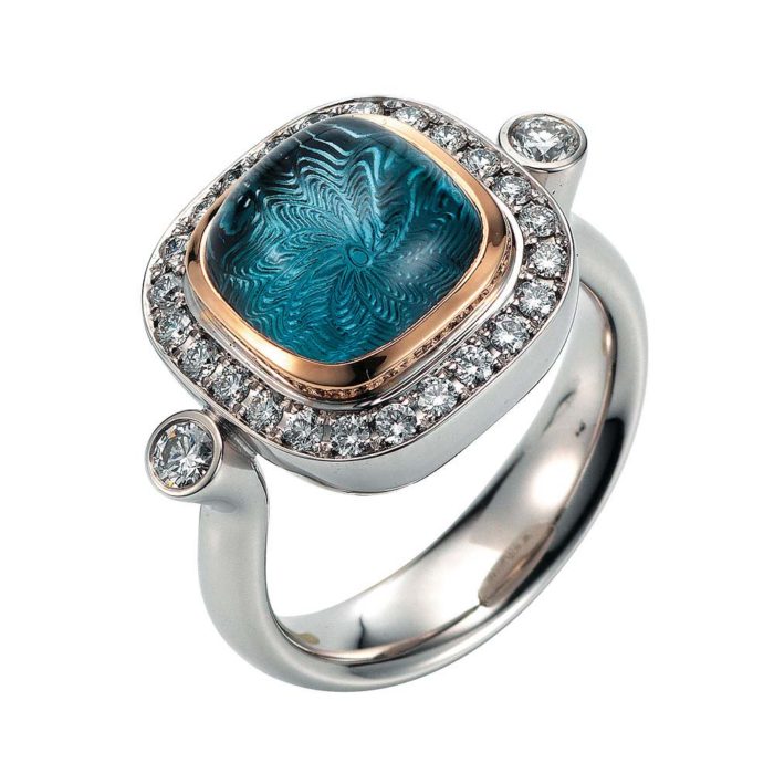 Gold ring with diamonds and blue gemstone on guilloched surface