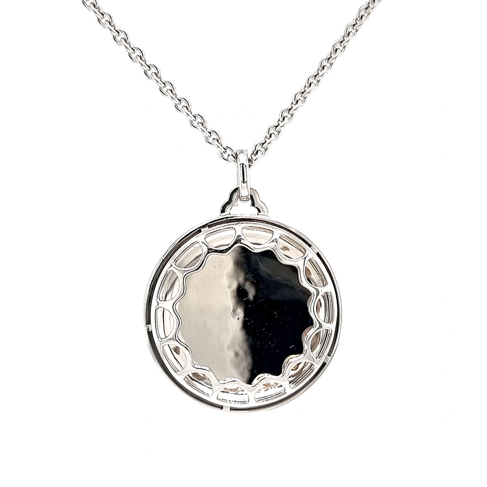 A round pendant on a chain. It is made of white gold and about the size of a large coin. The surface shines in a rich ruby-red colour with a wavy pattern. Across it runs a large flower shape made of many small diamonds. The pendant hangs from a fine chain.