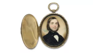 Ovaler, offener Medaillonanhänger mit Aquarell auf Elfenbein, männliches Porträt eines Mannes in schwarzem Anzug und Krawatte mit Bar. Der Anhänger ist goldfarben.