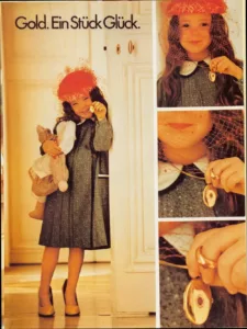 Advertisement featuring a girl dressed in a grey skirt and with a ladies red head with veil and ladies shoes that are both too large for her. Holding in her right arm a baby doll and in her lieft hand an oval gold locket pendant that is hanging from her neck and with a gold ring on her middle finger both with ornamented with diamonds and a oval shaped red gemstone.