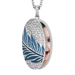 Oval white gold oval locket pendant covered with various white gemstones and ornamented with a leave motive in two tones of blue colour hanging from a white gold chain.