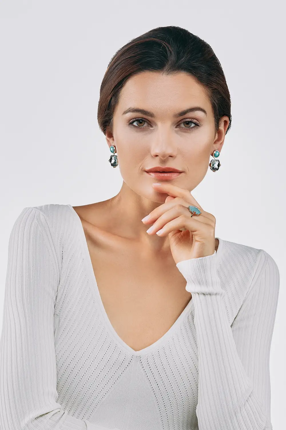 Female model with ring and earrings with blue, cushion-shaped, faceted gemstones,1000x1500. Vertical picture.