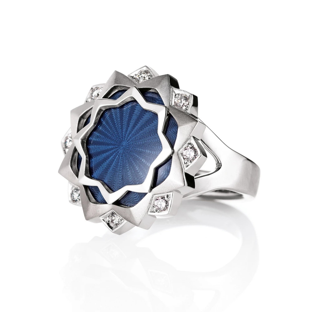 Ring Chrysanthemum: 18kt white gold, indigo blue vitreous enamel, guilloche engraving by hand, 8 diamonds, total 0.20 ct, G VS, diameter of ring head 21,5 mm. Limited edition of 50 pieces. V1696-HB-00-00-105,1000×1000 Silver-coloured, round ring with star-shaped decoration and blue, transparent colour, under which fine wave patterns are visible. Set all round with 8 white diamonds,1000x1000.