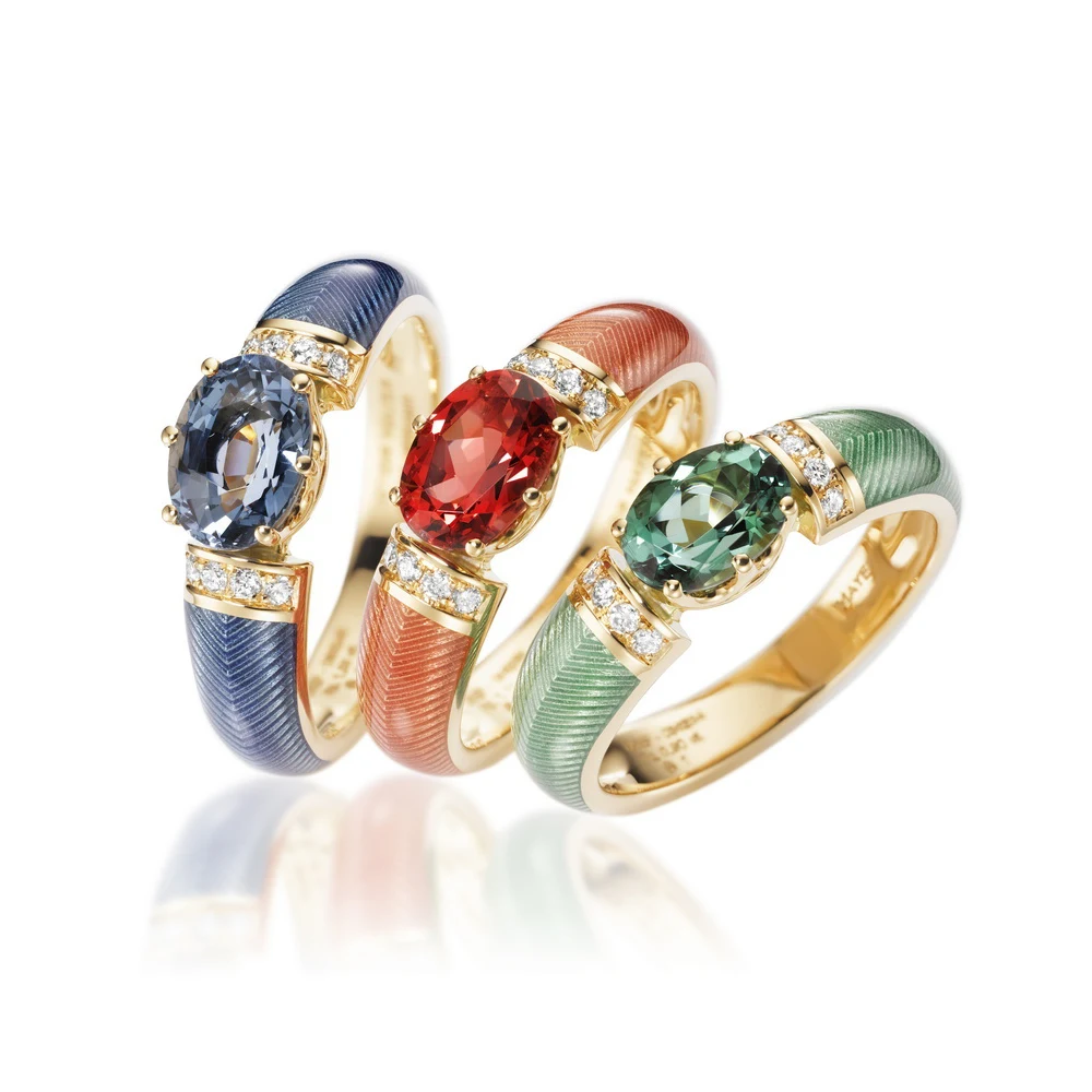 Three gold rings with colourful oval gemstones, each ring with two stripes of small white diamonds. The rings are covered in transparent colour, under which a fine thread pattern is visible,1000x1000.