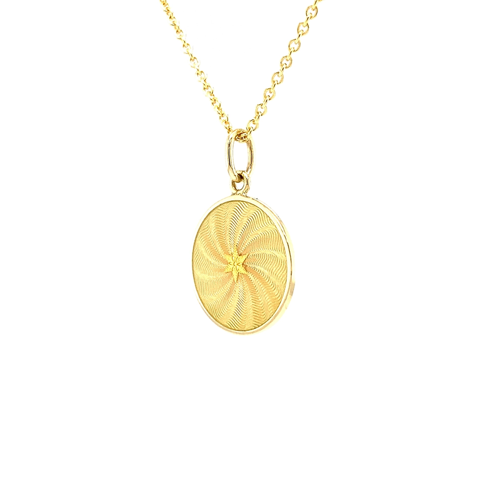 Small round pendant made of yellow gold, about the size of a small coin. The front shimmers in golden yellow translucent enamel with a fine wave pattern. At the center lies a tiny hexagonal gold insert shaped as a star with microscopic relief details.