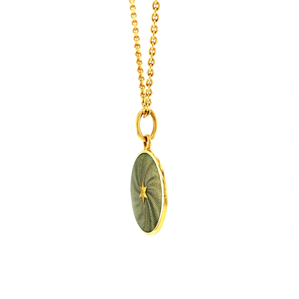 Kleiner runder Anhänger aus Gelbgold, etwa so groß wie eine kleine Münze. Die Vorderseite schimmert in transluzider hellgrauer Emaille mit feinem Wellenmuster. In der Mitte liegt ein winziges sechseckiges Goldplättchen in Sternform mit mikroskopisch feinen Reliefdetails.