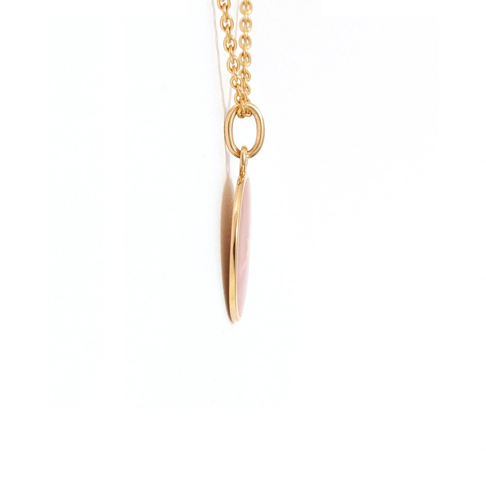 Small round pendant made of yellow gold, about the size of a small coin. The front shimmers in pink translucent enamel with a fine wave pattern. At the center lies a tiny hexagonal gold insert shaped as a star with microscopic relief details.
