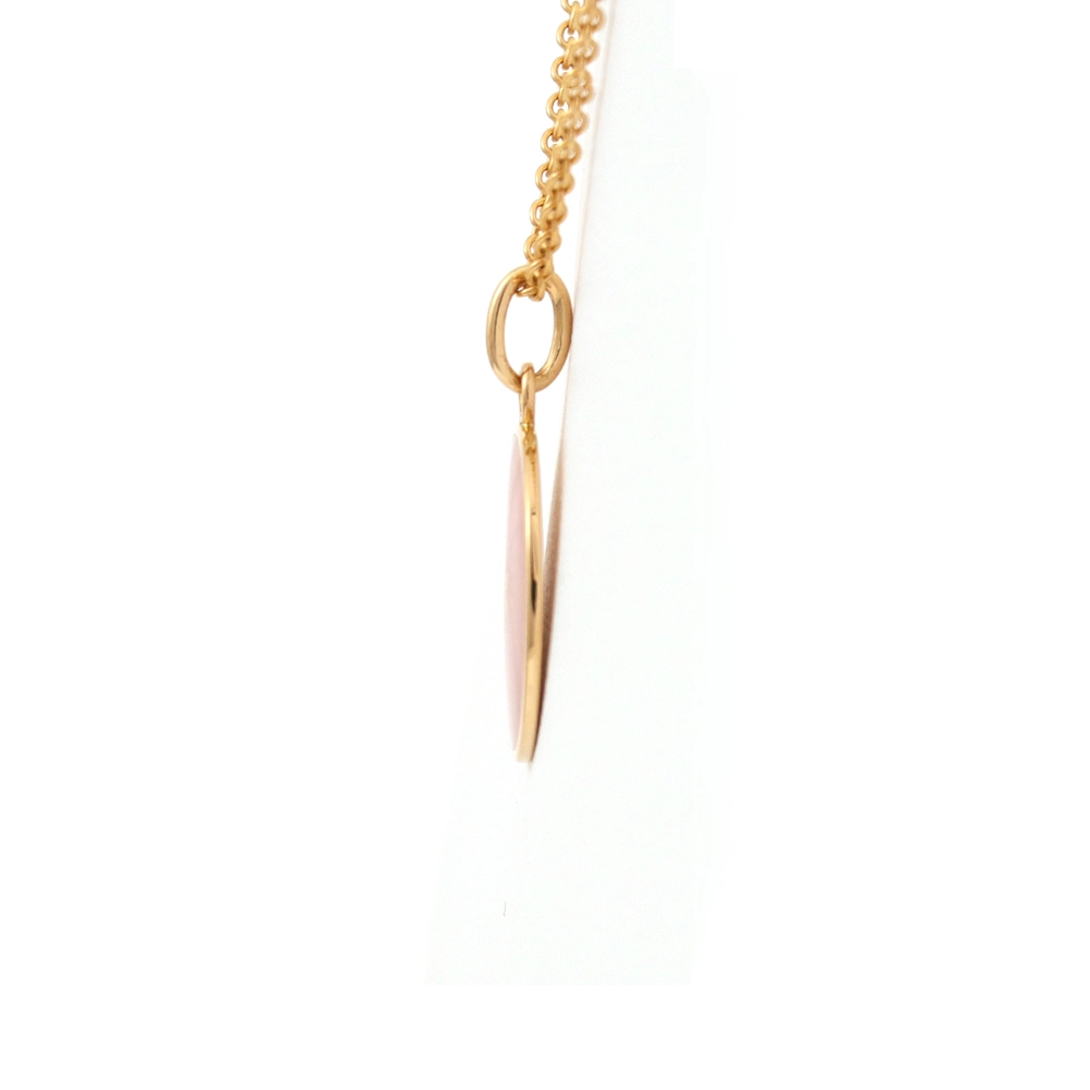 Small round pendant made of yellow gold, about the size of a small coin. The front shimmers in pink translucent enamel with a fine wave pattern. At the center lies a tiny hexagonal gold insert shaped as a star with microscopic relief details.