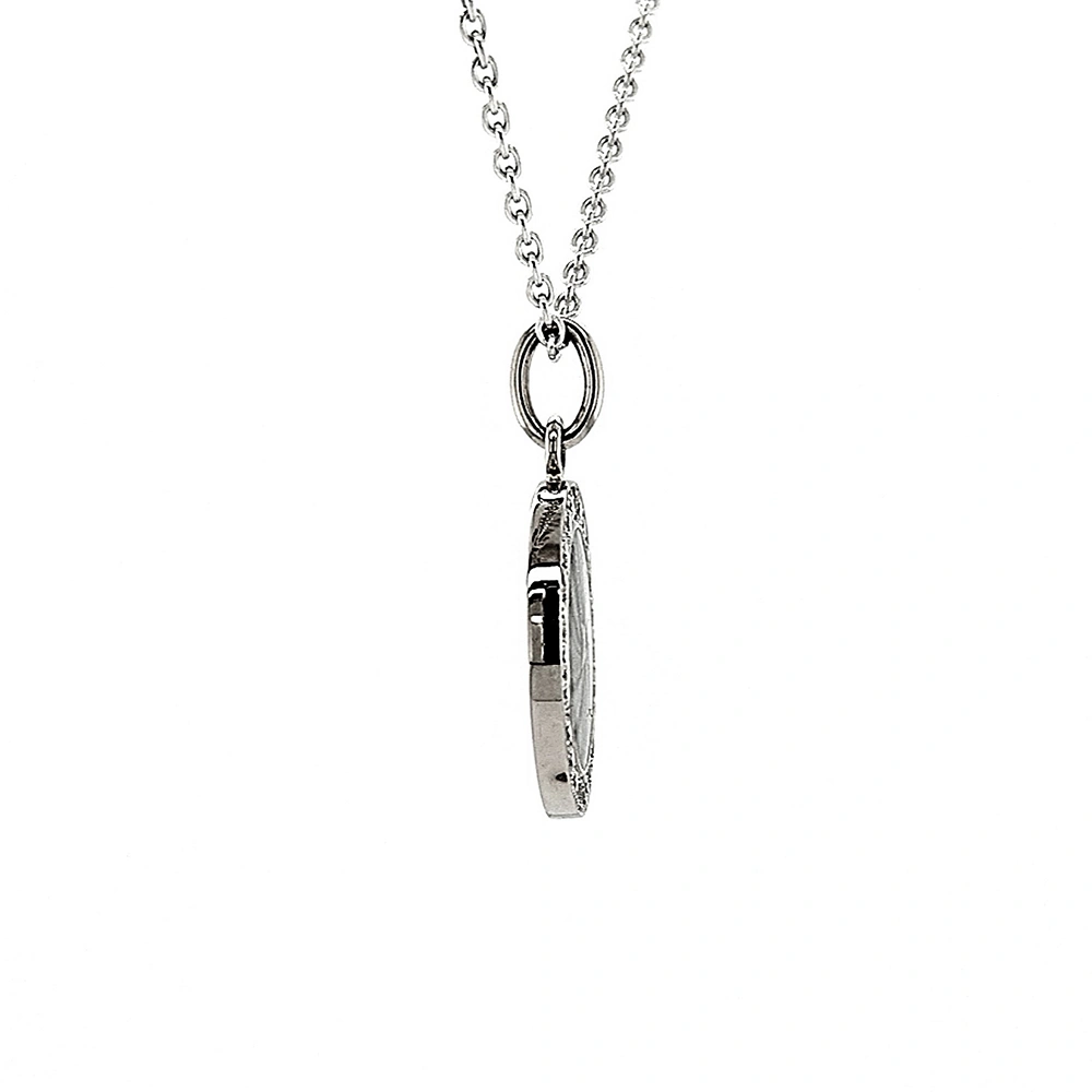 Small round pendant made of white gold, about the size of a small coin. The front shimmers silver-grey in translucent enamel with a fine wave pattern. At the center lies a tiny hexagonal star-shaped gold insert, surrounded by 24 sparkling diamonds.