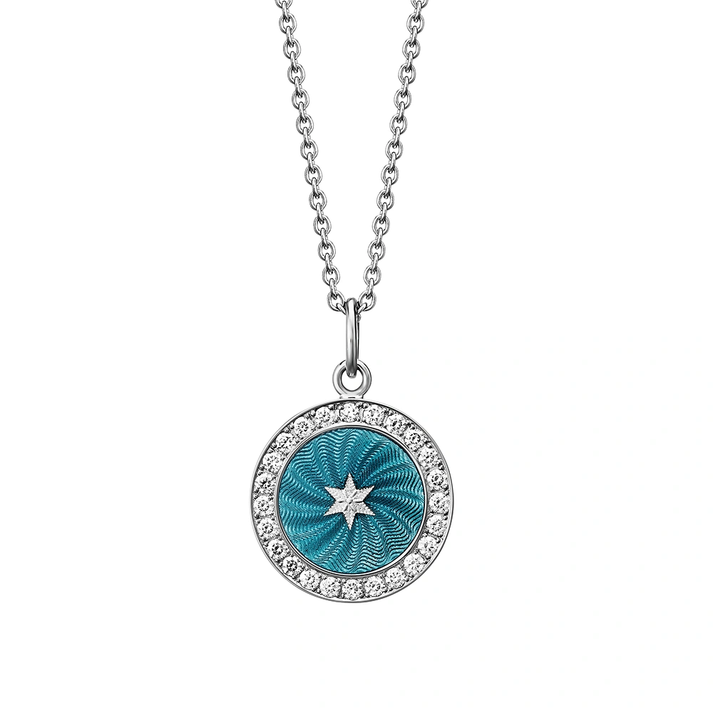 Small round pendant made of white gold, about the size of a small coin. The front shimmers turquoise in translucent enamel with a fine wave pattern. At the center lies a tiny hexagonal star-shaped gold insert, surrounded by 24 sparkling diamonds.
