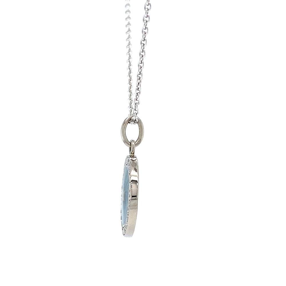 Small round pendant made of white gold, about the size of a small coin. The front shimmers turquoise in translucent enamel with a fine wave pattern. At the center lies a tiny hexagonal star-shaped gold insert, surrounded by 24 sparkling diamonds.