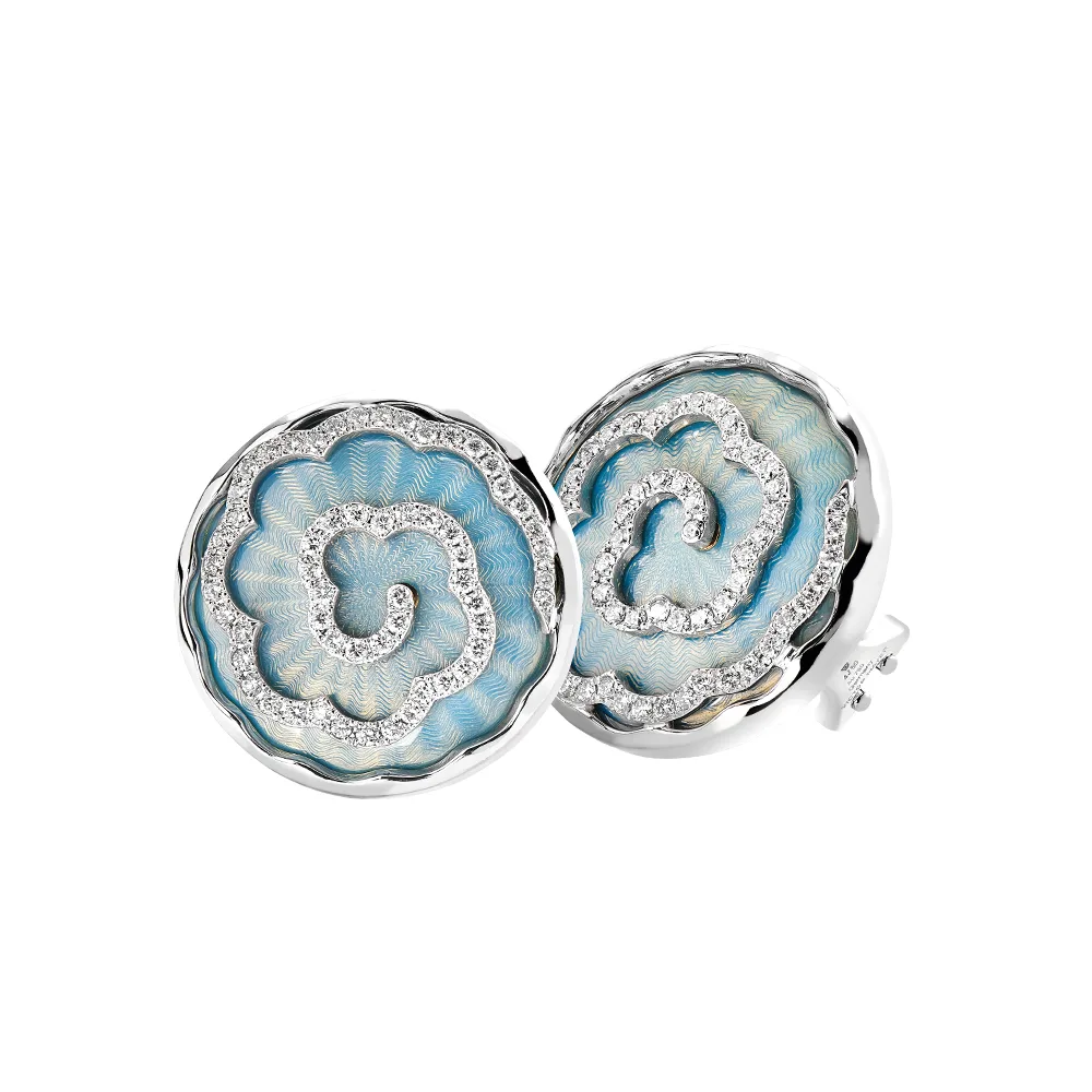 Ein Paar runde Ohrringe aus Weißgold. Der Ohrschmuck hat etwa die Größe einer Münze. Die Oberfläche schimmert in einem kräftigen Opal-Türkis-Ton mit einem wellenartigen Muster. Darüber liegt die Form einer großen Blüte, besetzt mit vielen kleinen Diamanten.