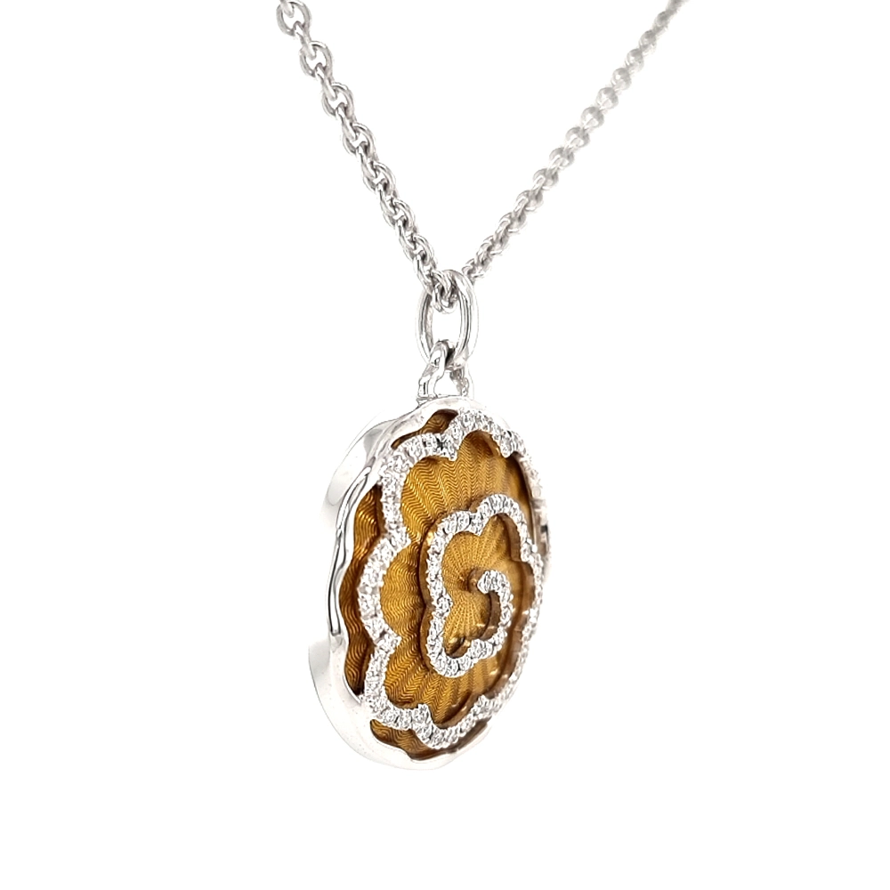 A round pendant on a chain. It is made of white gold and about the size of a large coin. The surface shines in a rich golden-amber colour with a wavy pattern. Across it runs a large flower shape made of many small diamonds. The pendant hangs from a fine chain.