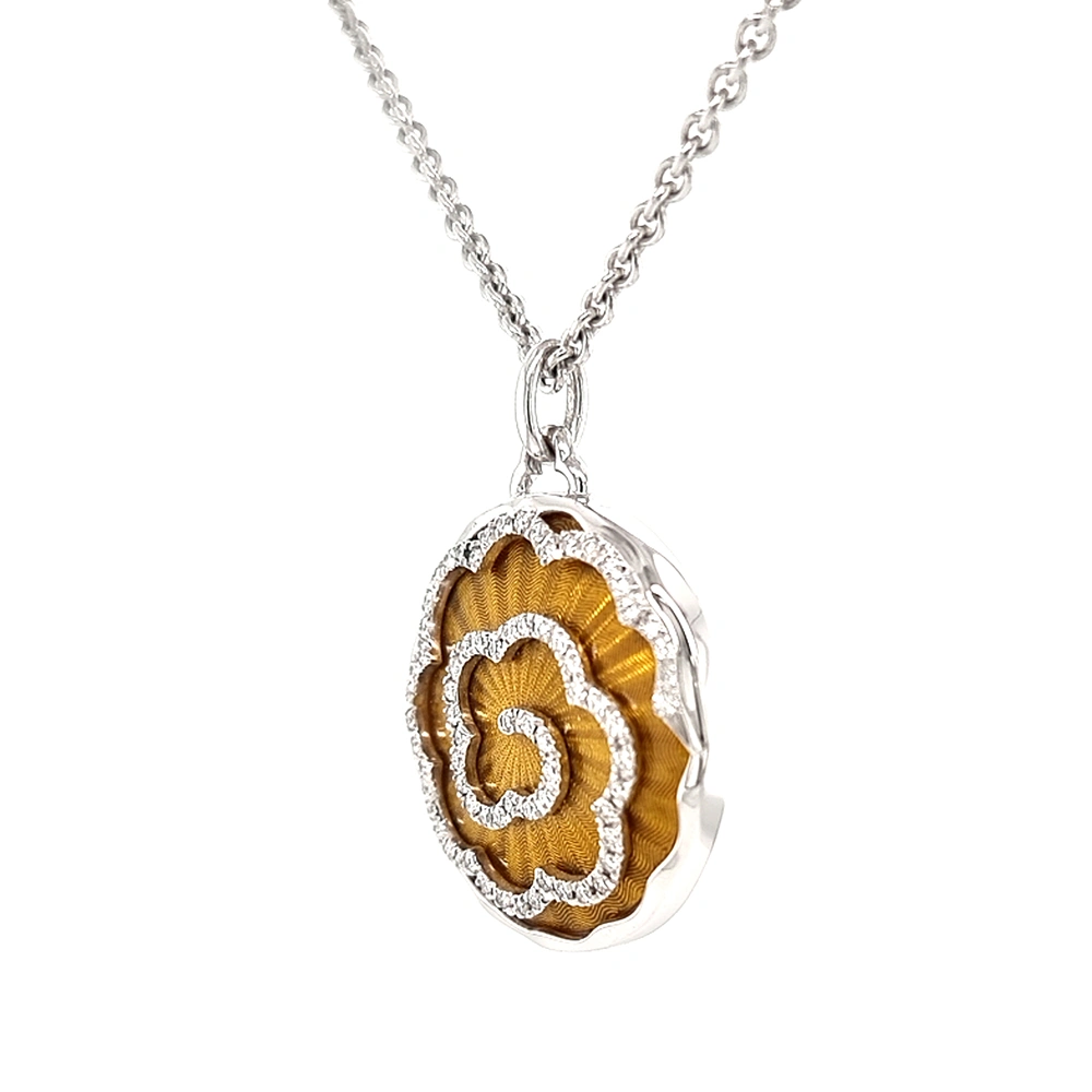 A round pendant on a chain. It is made of white gold and about the size of a large coin. The surface shines in a rich golden-amber colour with a wavy pattern. Across it runs a large flower shape made of many small diamonds. The pendant hangs from a fine chain.