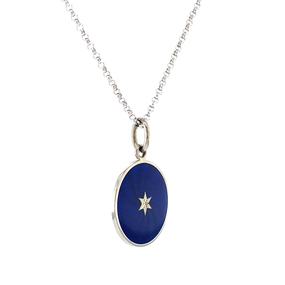 Small round pendant made of white gold, about the size of a small coin. The front shimmers in electric blue translucent enamel with a fine wave pattern. At the center lies a tiny hexagonal gold insert shaped as a star with microscopic relief details.