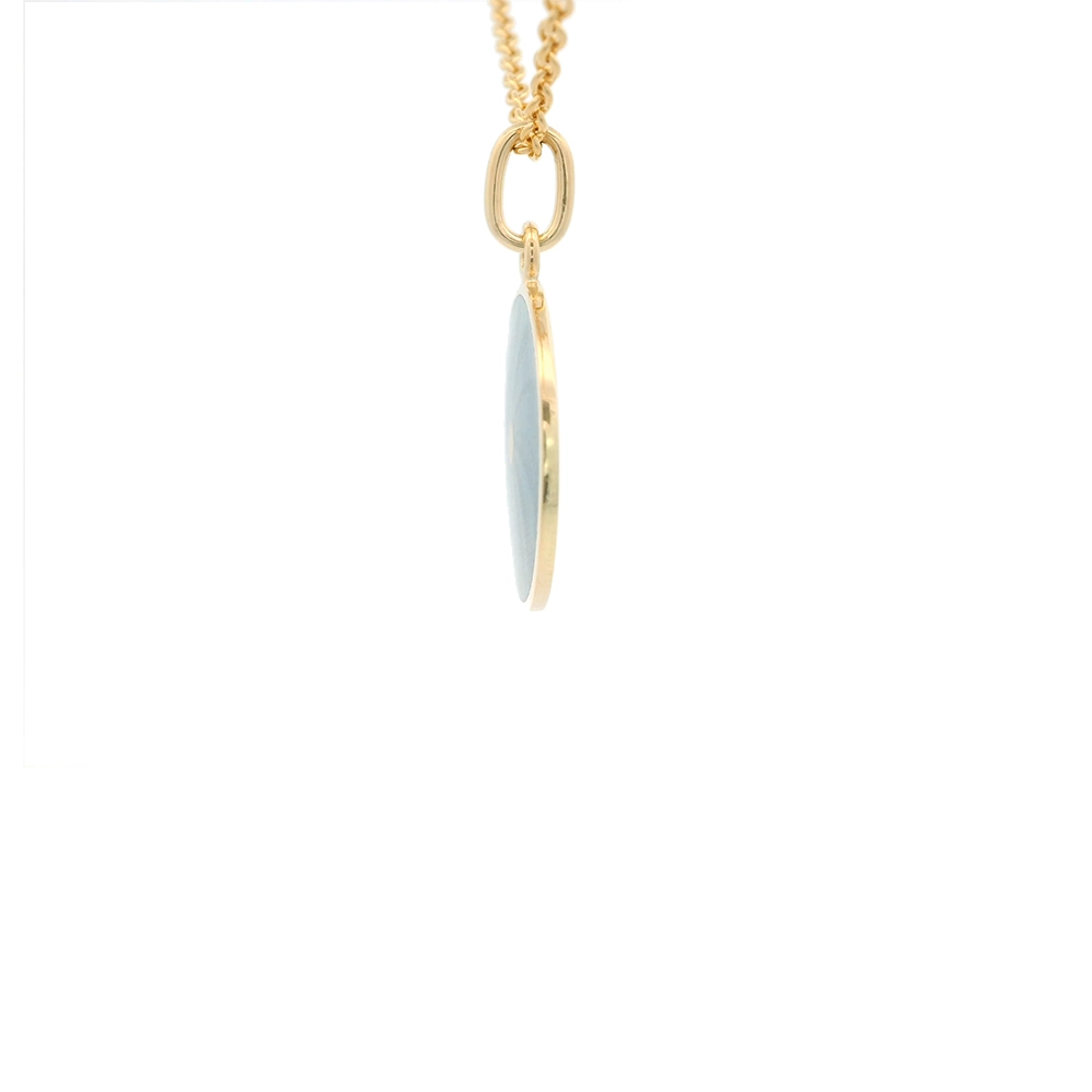 Kleiner runder Anhänger aus Gelbgold, etwa so groß wie eine kleine Münze. Die Vorderseite schimmert mediumblau in durchscheinender Emaille mit feinem Wellenmuster. In der Mitte ist ein winziges sechseckiges Goldplättchen eingelassen, das die Buchstaben V und M als Relief zeigt.
