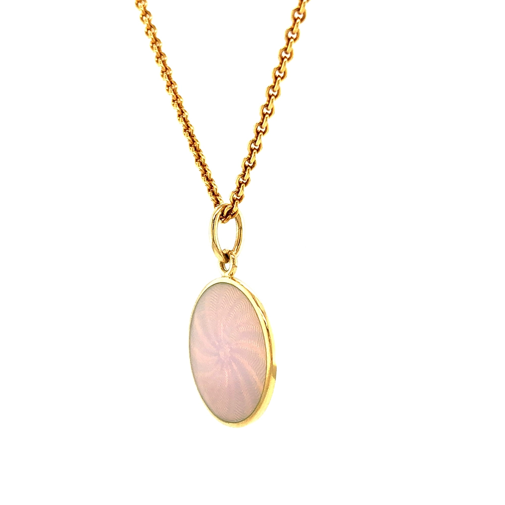 Small round pendant made of yellow gold, about the size of a small coin. The front shimmers in opalescent white, shifting colours like an opal when catching the light. A fine wave pattern appears beneath the enamel.