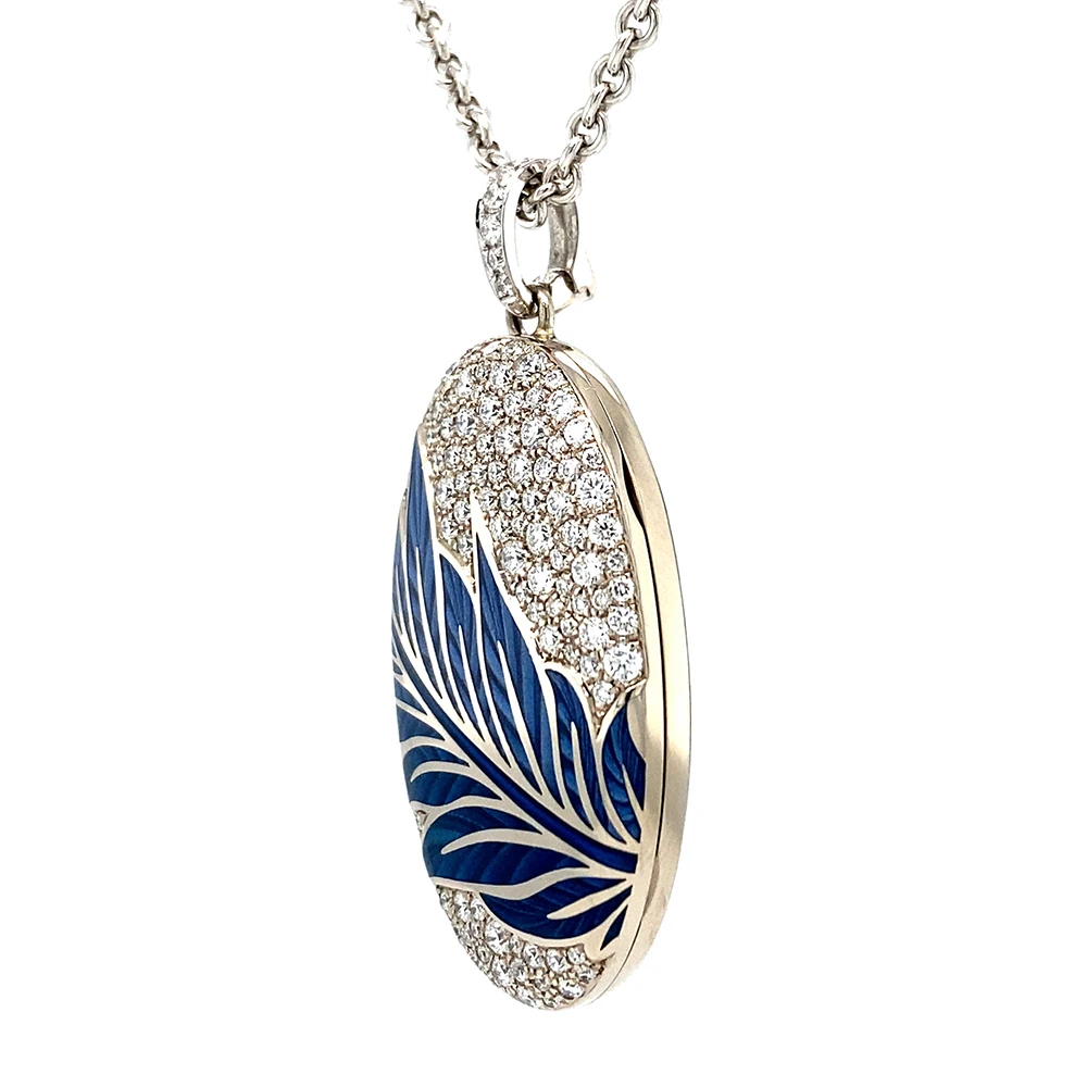 Ovaler Medaillon-Anhänger mit Brillant-Pavé und blauem quer verlaufendem Blättermotiv. Die Blätter sind mit zwei Emaille-Farbtönen emailliert. Das Medaillon lässt sich seitlich öffnen und enthält zwei Fotorahmen.