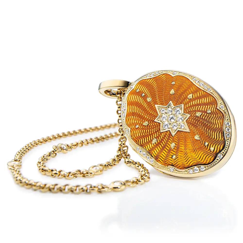 Oval locket pendant in yellow gold, lacquered autumn yellow with a multitude of small golden dots and a star made of diamonds in the centre.