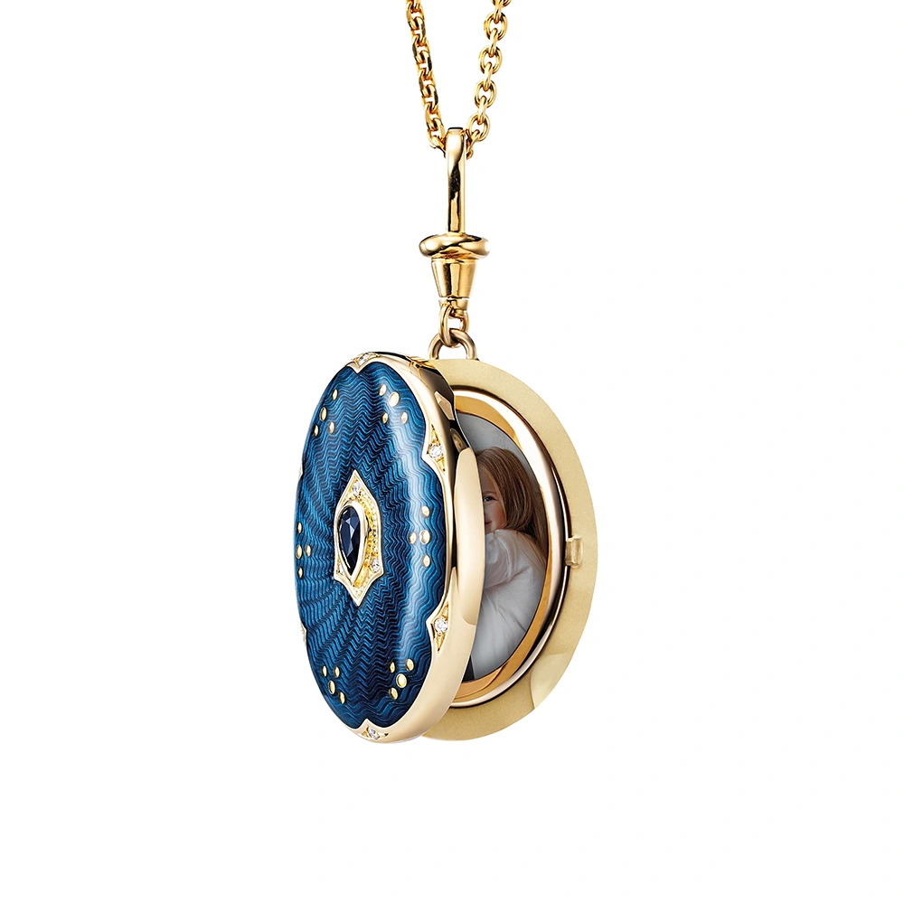Ovaler Medaillon-Anhänger aus Gelbgold, blau lackiert mit zahlreichen kleinen Goldpunkten und mit einem tropfenförmigen blauen Edelstein in der Mitte.