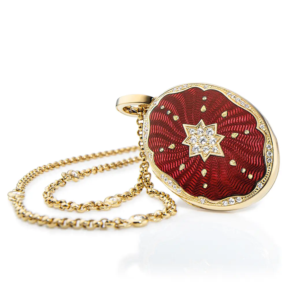 Ovaler Medaillon-Anhänger aus Gelbgold, rot lackiert mit einer vielzahl kleiner goldener Punkte und mit einem Stern aus Brillanten in der Mitte.