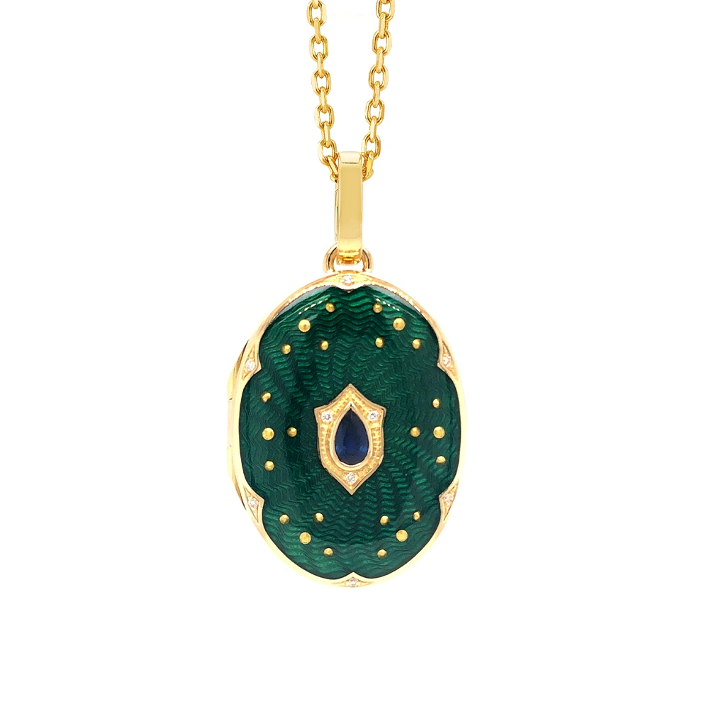 Ovaler Medaillon-Anhänger aus Gelbgold, grün lackiert mit zahlreichen kleinen Goldpunkten und mit einem tropfenförmigen blauen Edelstein in der Mitte.