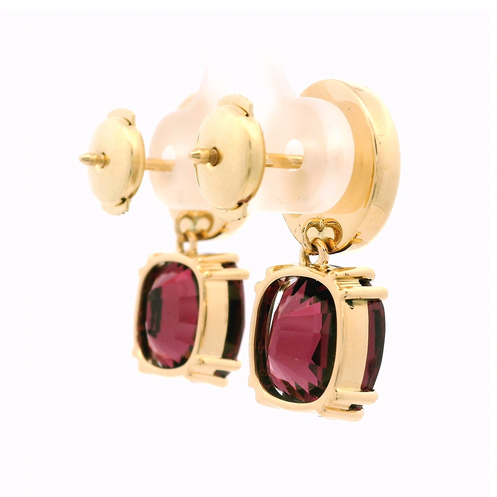 Pair of yellow-gold earrings with red cushion-cut rhodolites in four-claw settings and round white enamel boutons with gold rims.