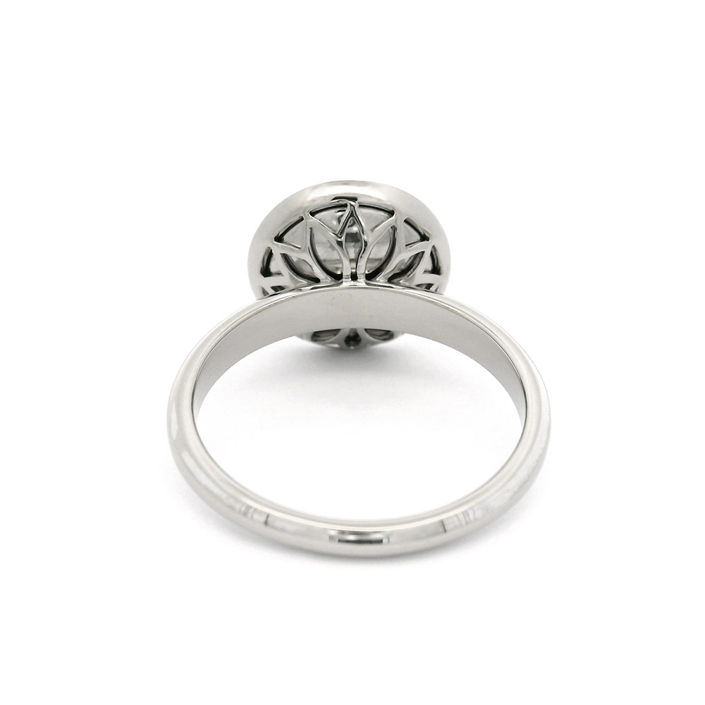 Ring aus Weißgold mit rundem Ringkopf. Der Ringkopf ist konkav gewölbt und mit mediumblauer transluzider Feueremaille versehen, unter der ein feines Windmühlen-Guilloché sichtbar ist. Im Zentrum der Emaillefläche sitzt ein einzelner kleiner Brillant als klarer Lichtpunkt. Die Gestaltung wirkt ruhig, geometrisch und ausgewogen.