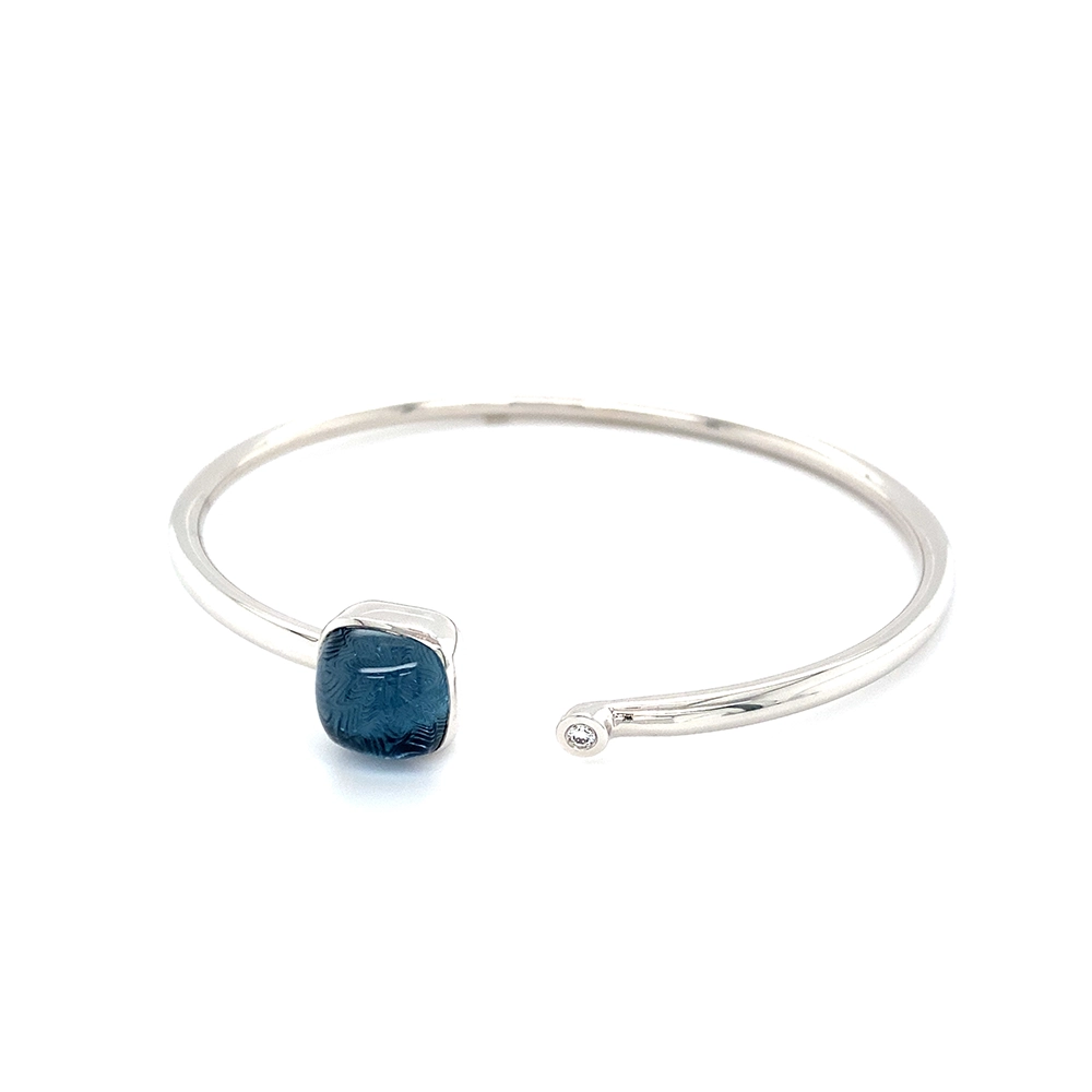 Era Bracelet in white gold with a cushion-cut blue topaz cabochon measuring 10 × 10 mm, a blue translucent gemstone set against a delicate guilloché wave pattern.