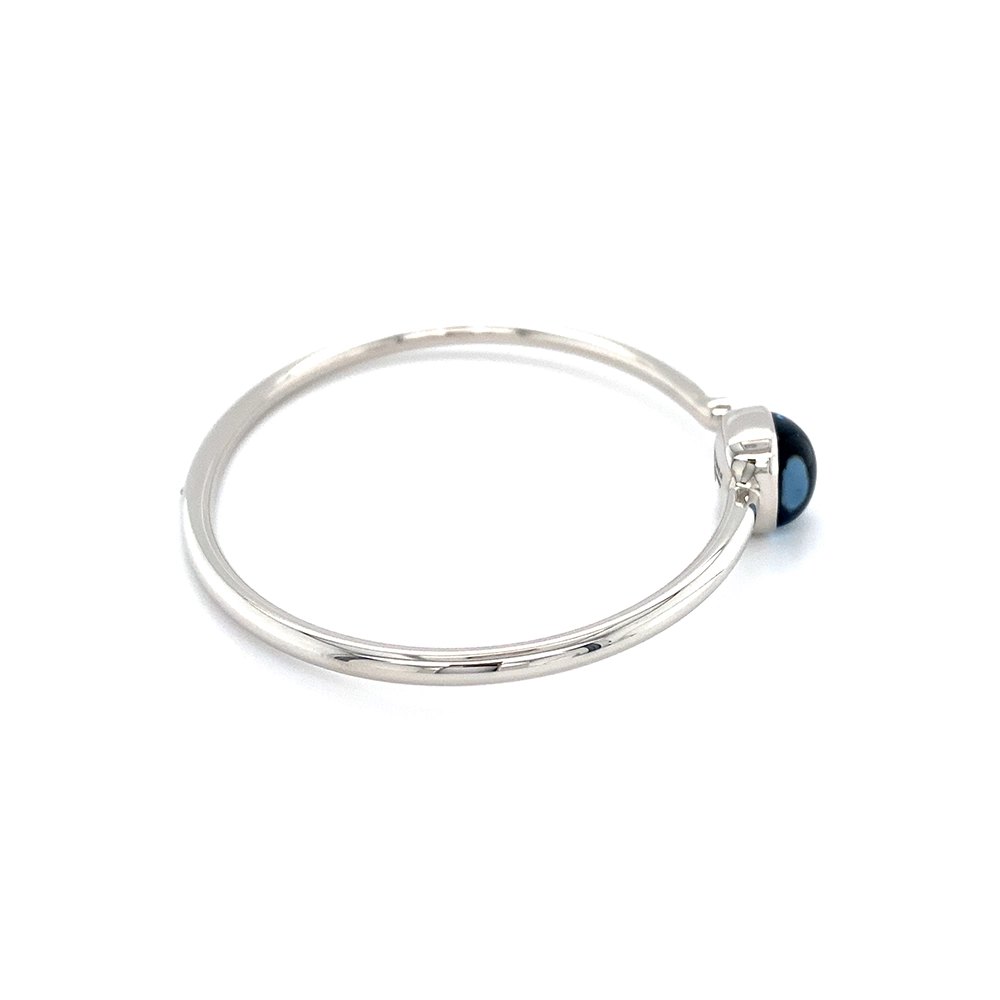 Era Bracelet in white gold with a cushion-cut blue topaz cabochon measuring 10 × 10 mm, a blue translucent gemstone set against a delicate guilloché wave pattern.