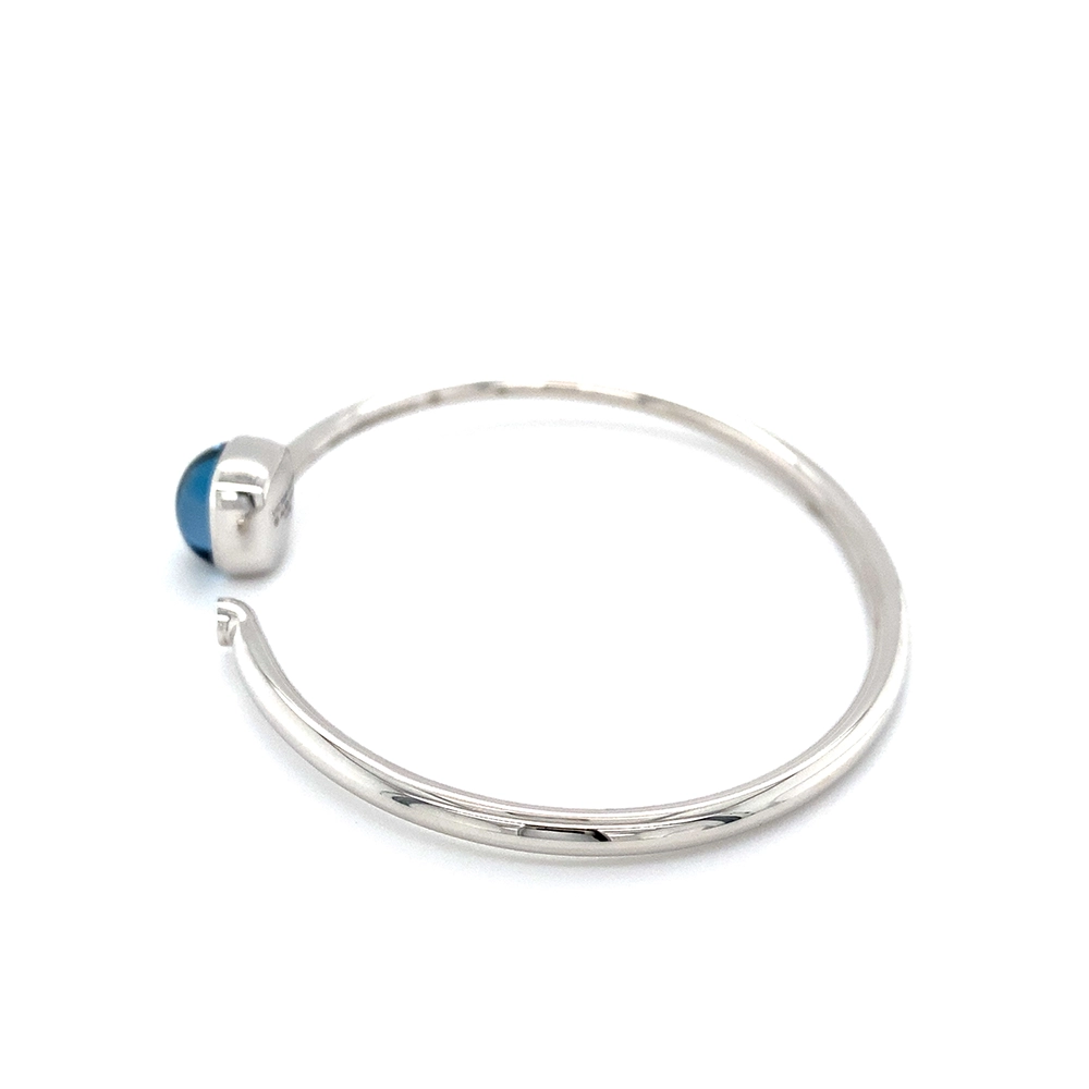 Era Bracelet in white gold with a cushion-cut blue topaz cabochon measuring 10 × 10 mm, a blue translucent gemstone set against a delicate guilloché wave pattern.