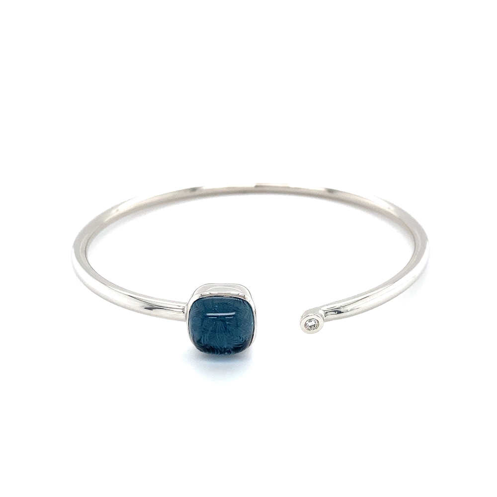 Era Bracelet in white gold with a cushion-cut blue topaz cabochon measuring 10 × 10 mm, a blue translucent gemstone set against a delicate guilloché wave pattern.