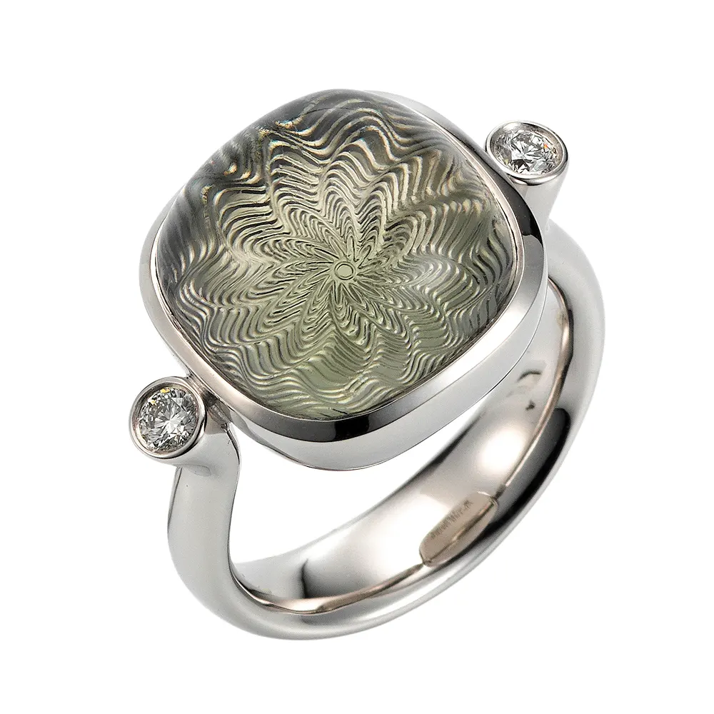 Era ring in white gold withEra Ring aus Weißgold mit kissenförmigem Prasiolith-Cabochon 14 x 14 mm, einem hellgrünen durchscheinenden Edelstein über einem feinen Guilloché-Wellenmuster a cushion-cut prasiolite cabochon measuring 14 x 14 mm, a pale green translucent gemstone set against a delicate guilloché wave pattern.